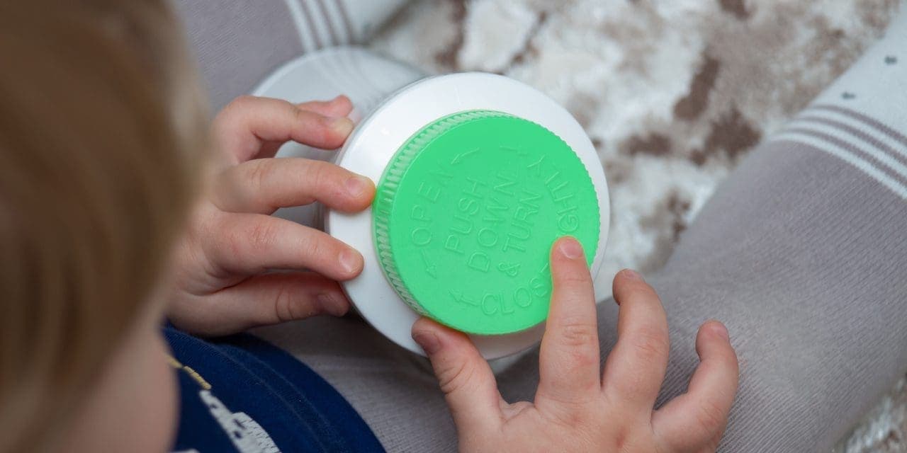 closeup of kid's hands holding the screw lid of plastic container