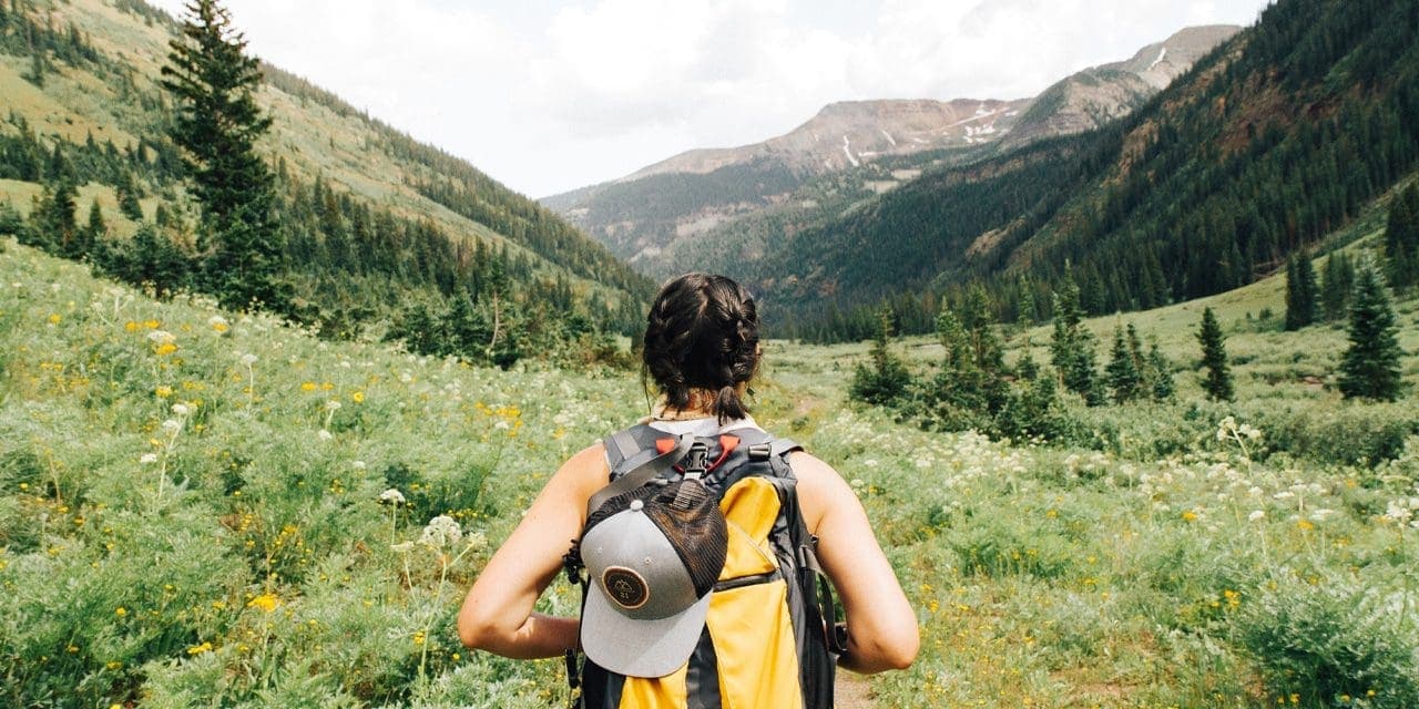 a woman wearing back pack in a mountain scenery