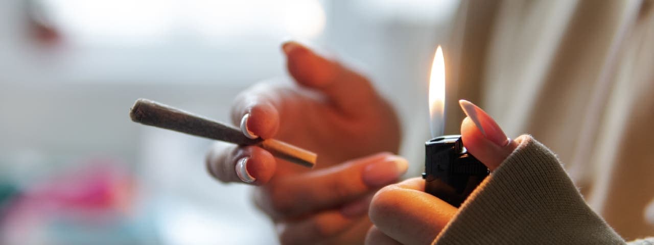 Close up of a person's hands about to light a cannabis-pre-roll with a lighter